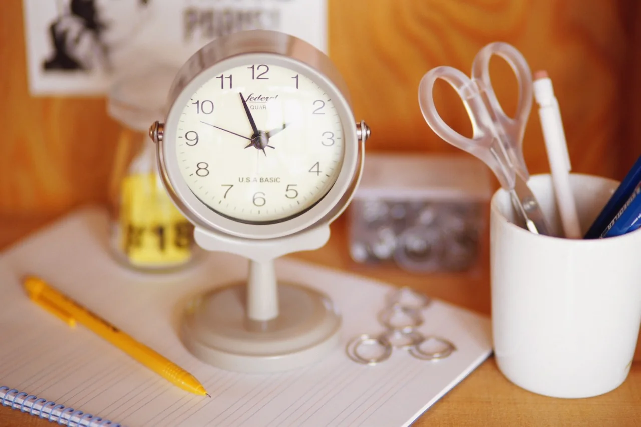 Reloj, cuaderno, lápiz y accesorios de oficina sobre un escritorio